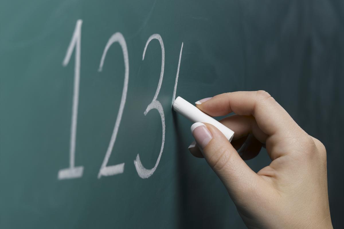 Una profesora escribiendo números en la pizarra.