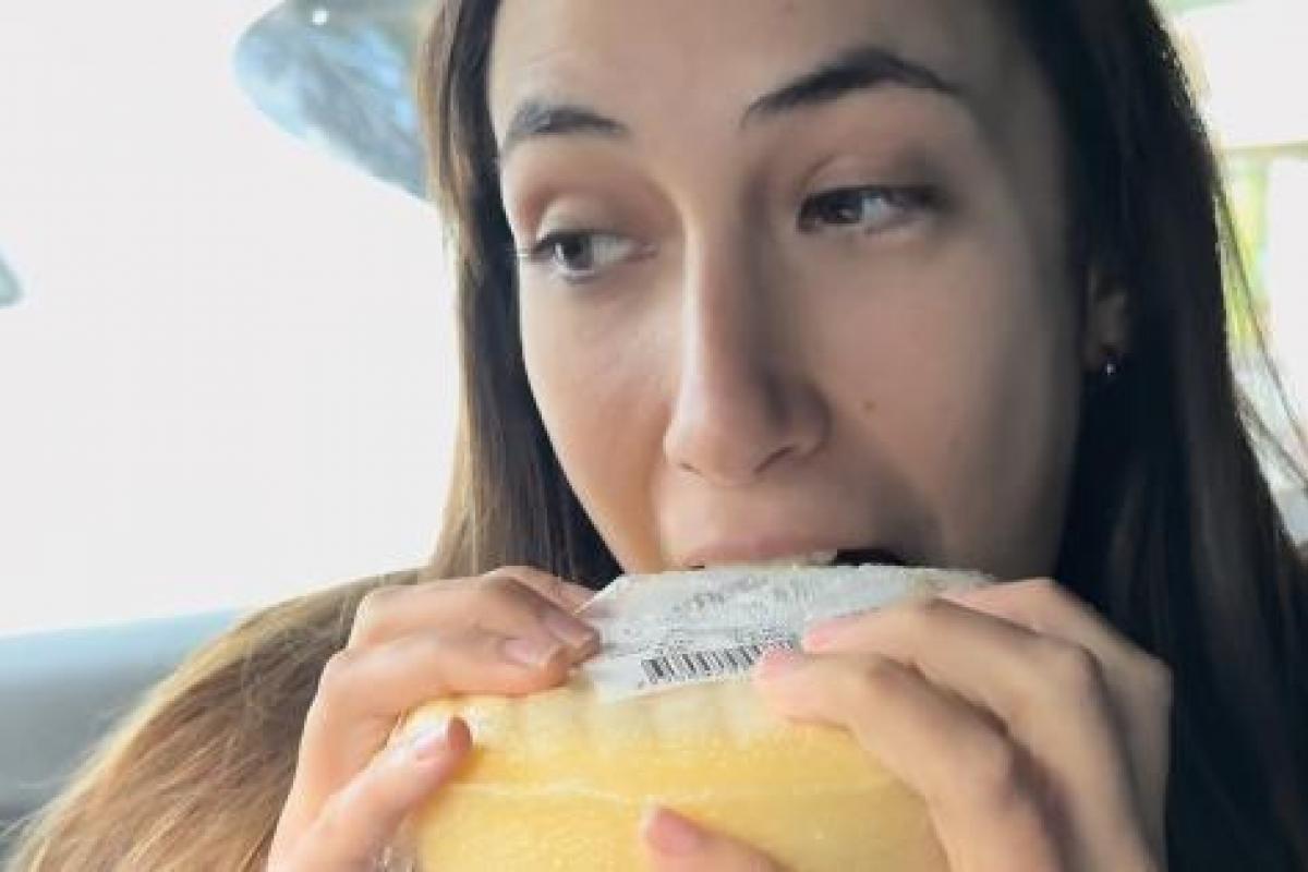 Joven dando un mordisco a un queso Arzúa-Ulloa en un coche mientras graba un vídeo para TikTok.