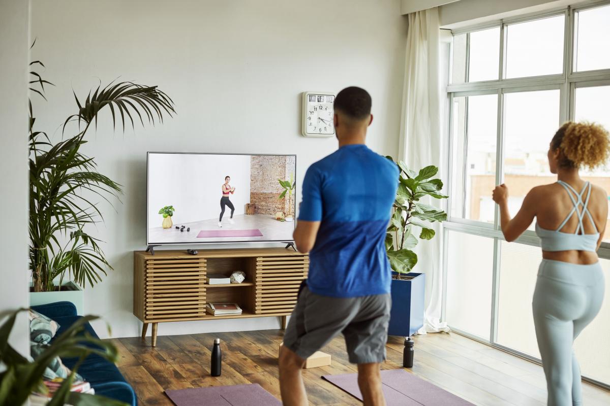 Una pareja haciendo ejercicio frente a una televisión.