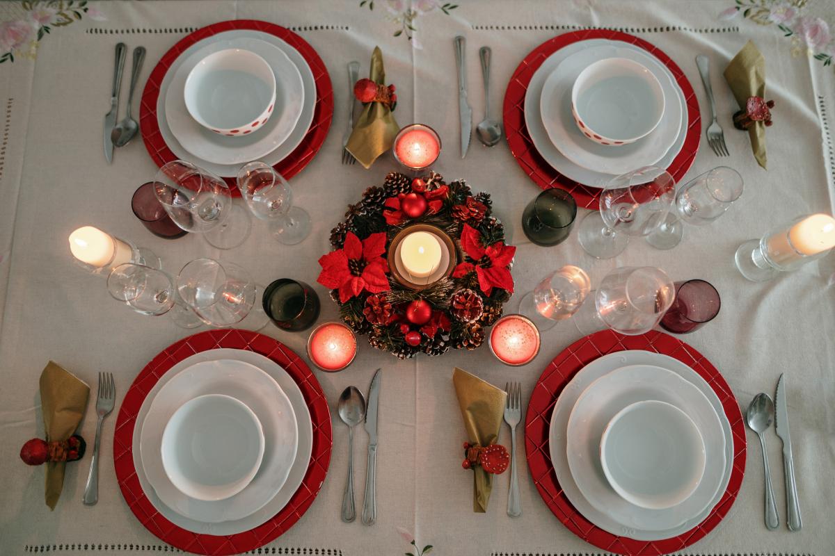 Mesa de Navidad con decoración clásica, bajoplatos rojos y cubertería colocada para la cena de Nochebuena.