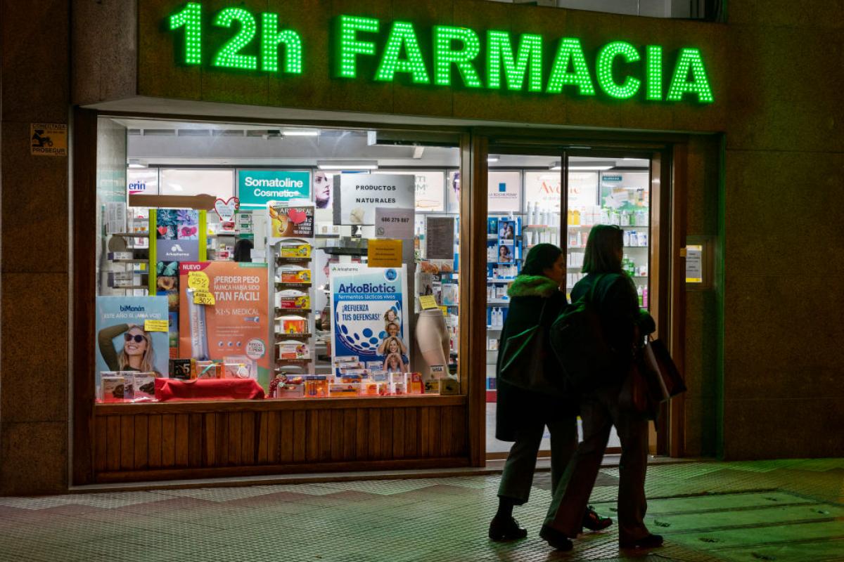 Unos peatones cruzan ante una farmacia, en Madrid, en una imagen de marzo de 2022.