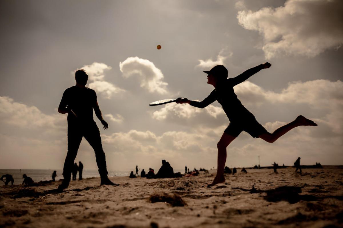 Un padre y su hijo jugando a las palas en una playa de Alemania.