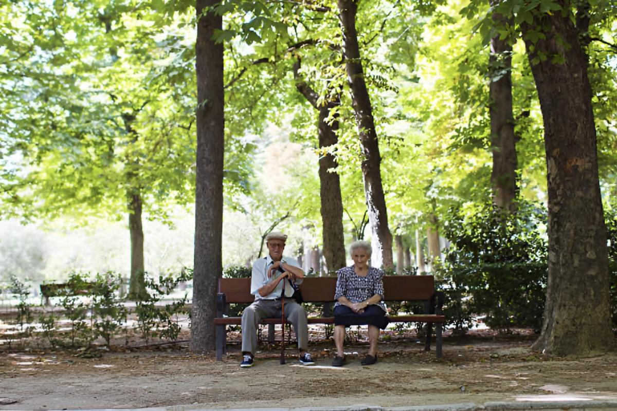 Dos ancianos sentados en un banco de un parque en Madrid
