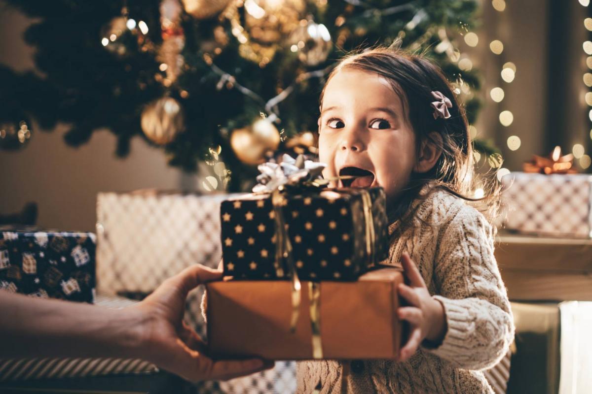 Encantadora niña pequeña recibiendo un regalo de Navidad