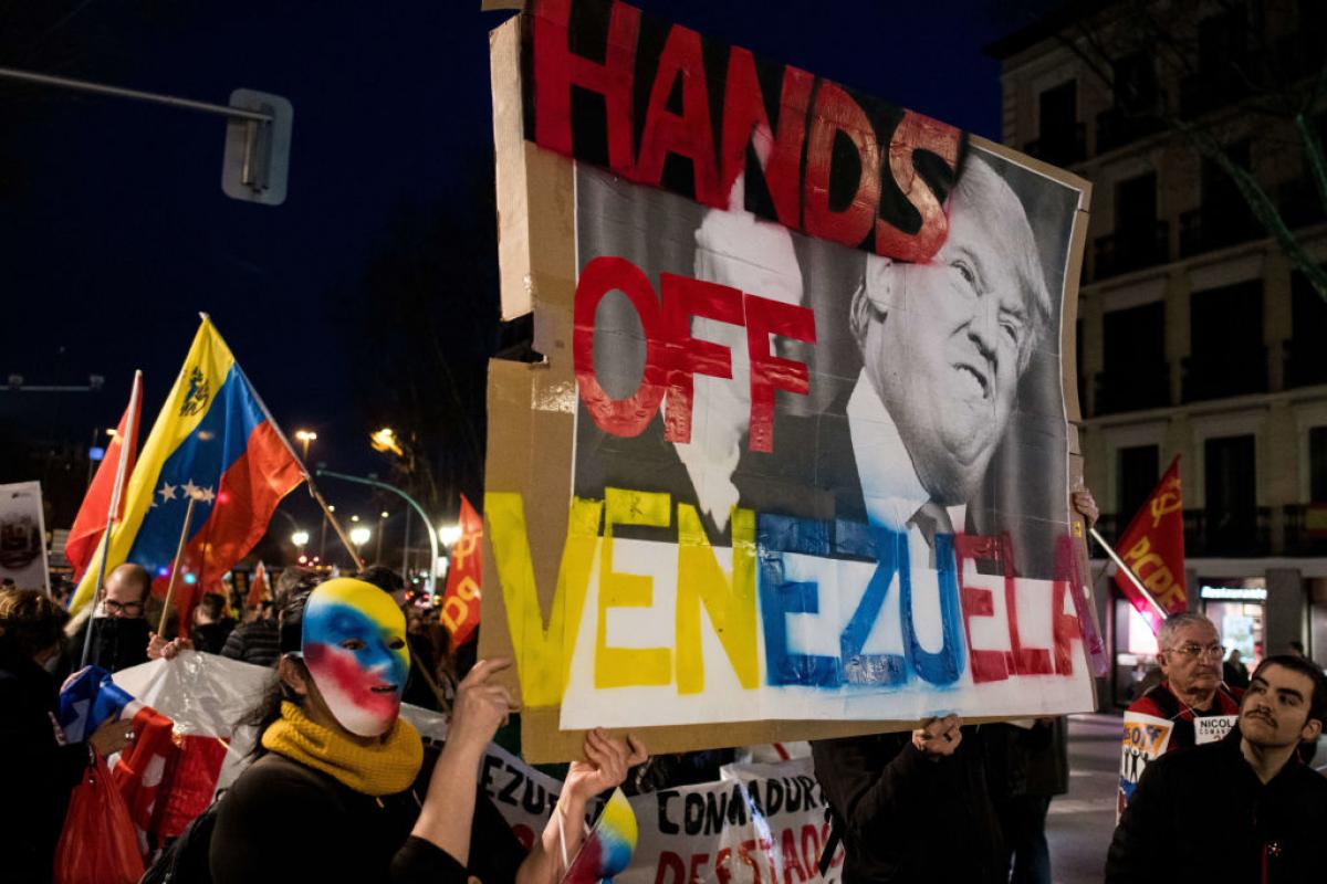 Una manifestante enmascarada porta una pancarta con la imagen del presidente de EEUU, Donald Trump, preclamando que "saque sus manos" de Venezuela, en febrero de 2019.