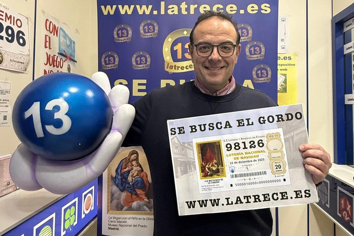 El lotero Jesús Ibáñez con el cartel informativo de 'Se busca el décimo'.