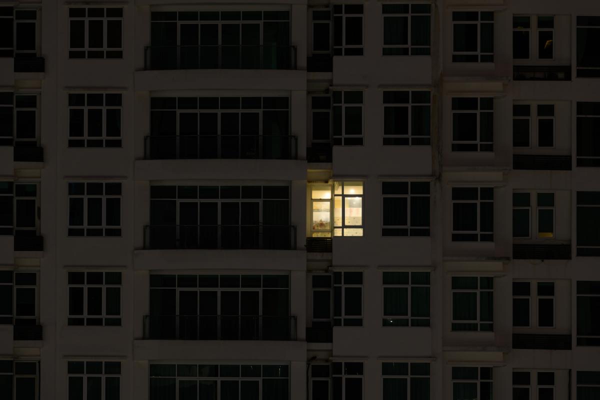 Imagen de archivo de la fachada de un edificio con solo una vivienda con la luz encendida.