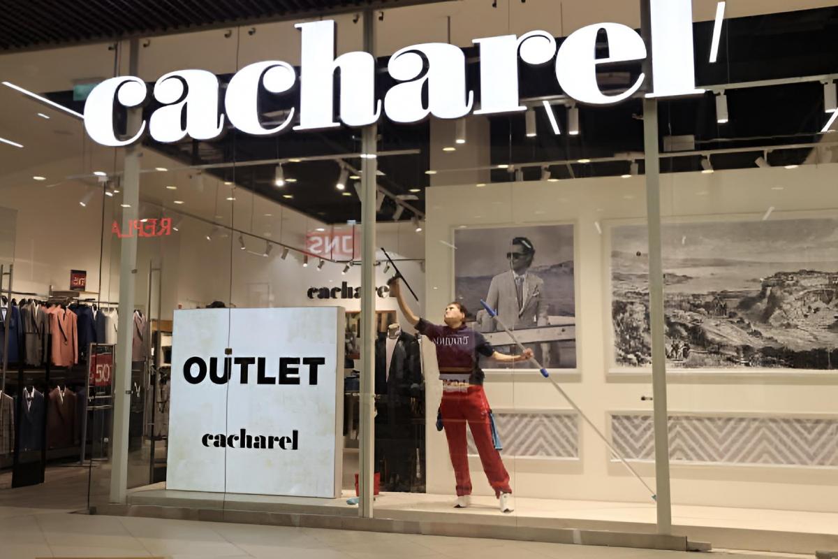 Una mujer limpiando el escaparate del outlet de Cacharel