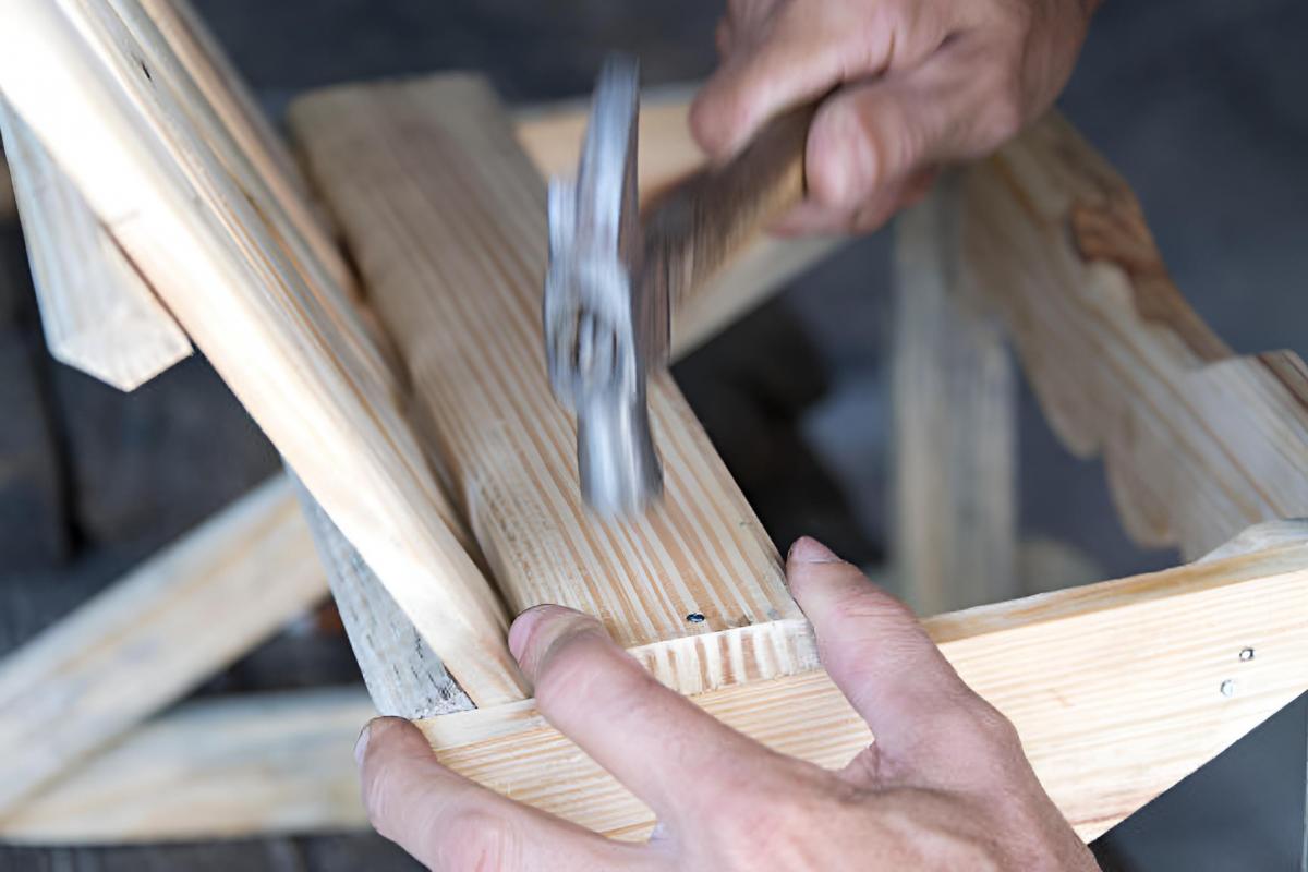 Un carpintero martillando clavos de metal en una construcción de madera