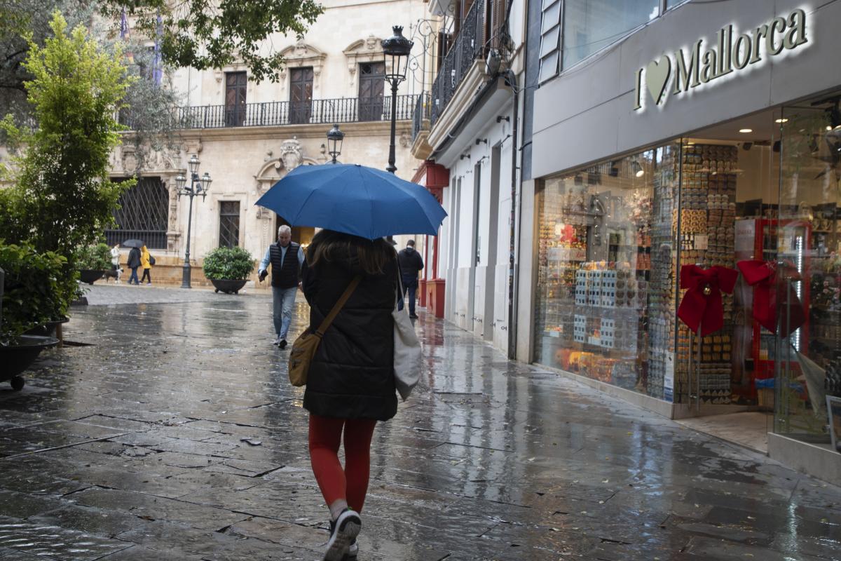 Una persona resguardándose de la lluvia con su paraguas.