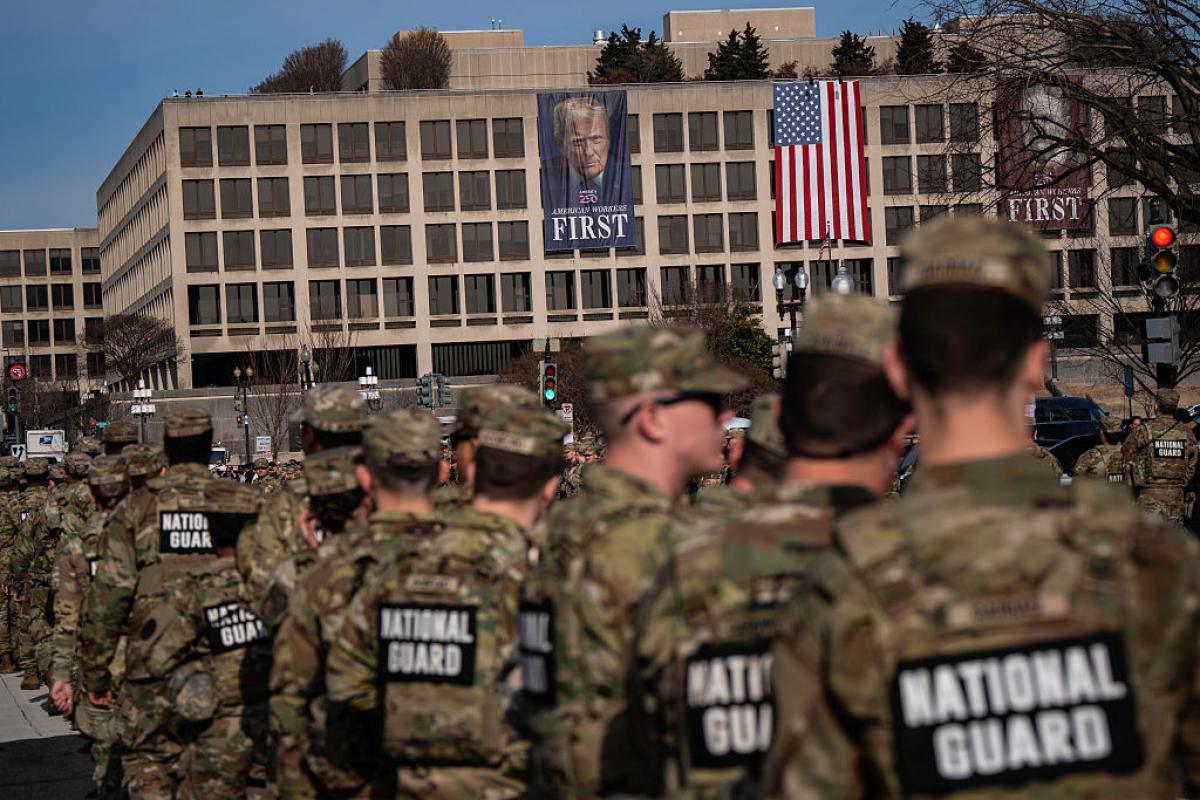 Miembros de la Guardia Nacional, el 8 de enero de 2026, en un desfile en honor a un agente caído, en Washington, con un cartel de Donald Trump al fondo.