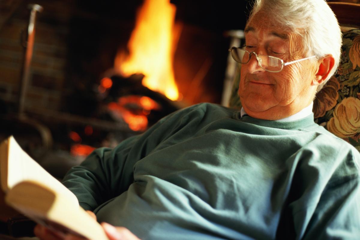 Un hombre de avanzada edad, leyendo al calor de la chimenea.