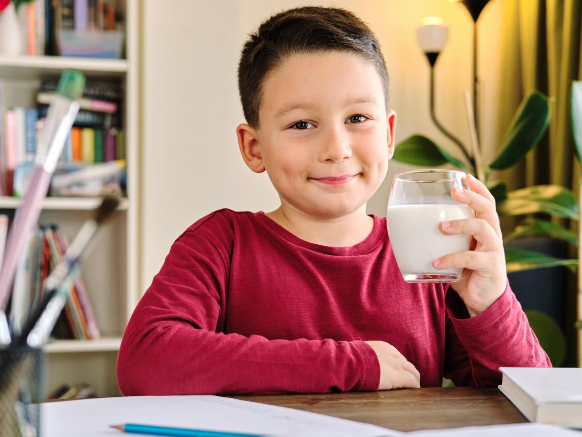 Un niño toma un vaso de leche antes de ir al colegio.