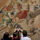 Tres técnicos realizan mediciones sobre el tapiz de Rafael