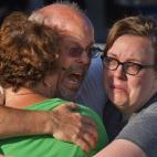 Tom Sullivan, center, embraces family members outside Gateway High School where he has been searching frantically for his son Alex Sullivan who celebrated his 27th birthday by going to see "The Dark Knight Rises," movie where a gunman opened fir...