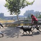 Dos vecinos con su perro con los rostros protegidos se alejan del incendio.