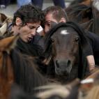 Dos hombres, en pleno esfuerzo durante la Rapa das bestas
