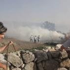 Vecinos de Valdefuentes (Salamanca) trabajan con mangueras para que el fuego no llegue a sus casas, a causa del fuerte viento.