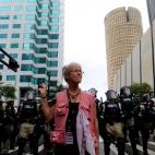 Una mujer hace el signo de la paz frente a un grupo de antidisturbios