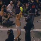 Un manifestante en ropa interior muestra una pancarta frente a la policía