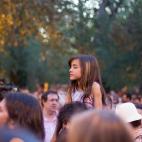 Una niña sigue los actos a hombros de un adulto