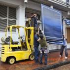 Unos trabajadores retiran una mampara de una tienda ante la amenaza de que la tormenta tropical Isaac alcance la región, en Nueva Orleans.