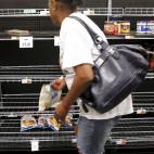 Una mujer elige algunos alimentos en un supermercado para prepararse ante la llegada del Isaac a Nueva Orleans. Las tiendas se han quedado vacías después de que la gente haya hecho acopio de provisiones.