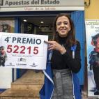 La propietaria de la administración número uno de las Torres de Cotillas (Murcia) Fuensanta Ortíz, muestra el cartel con el cuarto premio de la Lotería de Navidad, el 52215, del que han vendido 15O décimos.