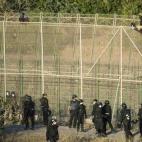 Los agentes fronterizos vigilan a varios inmigrantes encaramados en la valla (12 de agosto).
