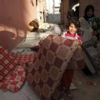 Una mujer con sus hijas vuelve a casa después de ocho días escondidas por las bombas. Más de 10.000 palestinos han perdido su hogar por la ofensiva israelí.
