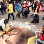 Artistas de la calle realizan un dibujo con la imagen de Jesús alusivo a la Navidad en una de las avenidas más concurridas de Lima.