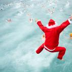 Un Papá Noel salta al agua en la tradicional competición en el muelle de Barcelona por la Copa de Navidad, que lleva ya 103 ediciones.