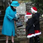 La reina Isabel II de Inglaterra recibe unas flores a manos de unas niñas vestidas de forma navideña a la salida de la misa a la que acude tradicionalmente la familia real británica el día de Navidad.