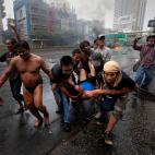 Mayo de 2010. Integrantes de los 'camisas rojas' trasladan a un hombre herido durante los enfrentamientos con los soldados armados en Bankok (Tailandia).