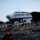 Marzo de 2011. Una miembro de la Cruz Roja pasa junto a los restos del tsunami que asol&oacute; la localidad de Otsuchi, al norte de Jap&oacute;n.