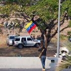 Un hombre ondea la bandera venezolana.