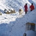 Dos personas pasean por la carretera comarcal CA-643 en la subida al puerto de Lunada por la red secundaria donde es obligatorio el uso de cadenas y donde esta activada la alerta por nevadas.