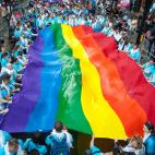 Una bandera gigante es sostenida por un grupo de miembros de Barclays en Londres.
