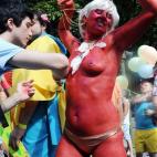 Un joven pinta el cuerpo de una mujer durante el Orgullo.