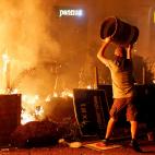 Un manifestante radical lanza una papelera al fuego