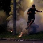 Un manifestante huye por el humo de un bote