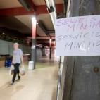Un cliente pasea por el Mercado de la Boquer&iacute;a con dos bolsas y un cartel de "Servicios m&iacute;nimos"