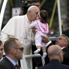 Pope Francis kisses a baby as he pauses in popemobile during a parade along the Benjamin Franklin Parkway in Philadelphia, Sunday, Sept. 27, 2015, on his way to celebrate Mass. (AP Photo/Carolyn Kaster)