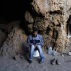 El camerunés Adria, sentado en su escondite de Ceuta junto a dos bidones de agua y un par de zapatos.