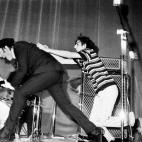 Beatles John Lennon continues to play the guitar as he evades a young fan who wants Lennon's yachting-style cap as a souvenir during the Beatles concert in Rome, Italy, June 28, 1965.