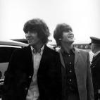 George Harrison and John Lennon from the Beatles pictured to looking at some of the hundreds of fans who turned up to see them leave London Airport for their trip to America.