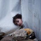 Una niña asoma la cabeza por la lona de su tienda de campaña en el campo de Azaz, en Siria. Su familia había escapado de los choques entre tropas leales al régimen de Damasco y milicianos del ELS (Ejército Libre de Siria).