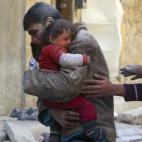 Un adolescente abraza a su pequeña hermana, recuperada de entre los escombros en la ciudad de Alepo, en febrero de 2014. Las tropas de El Asad atacaron la zona con bombas de barril, que consisten en un barril de petróleo, una bombona de gas o ...