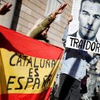 Demonstrators gesture as they hold a Spanish flag reading "Catalonia is Spain" and a defaced image of Spain's Prime Minister Pedro Sanchez reading "Traitor" during a rally in protest against the new coalition government led by Spain's Prime Mini...