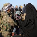 Una miliciana kurda atiende a una de las civiles rescatadas de la ciudad siria, junto a su beb&eacute;.